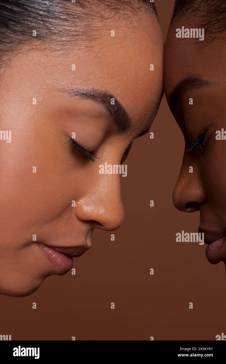 Junge Frauen mit geschlossenen Augen vor braunem Hintergrund Stockfoto