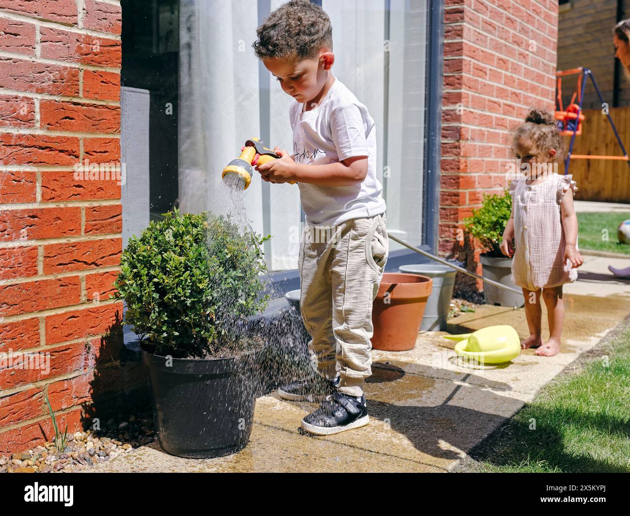 Junge, der Topfpflanzen im Garten gießt Stockfoto