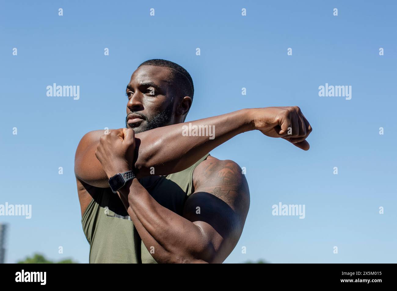 Mittelerwachsener Mann, der sich unter blauem Himmel ausdehnt Stockfoto
