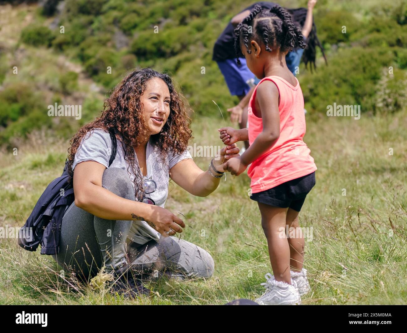 Mutter mit Kleinkind-Tochter, die Gras aufnimmt Stockfoto