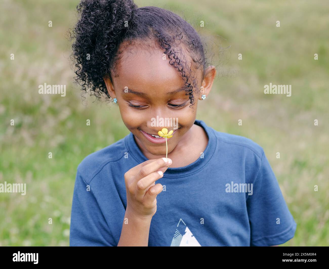 Lächelndes Mädchen, das nach Blumen riecht Stockfoto