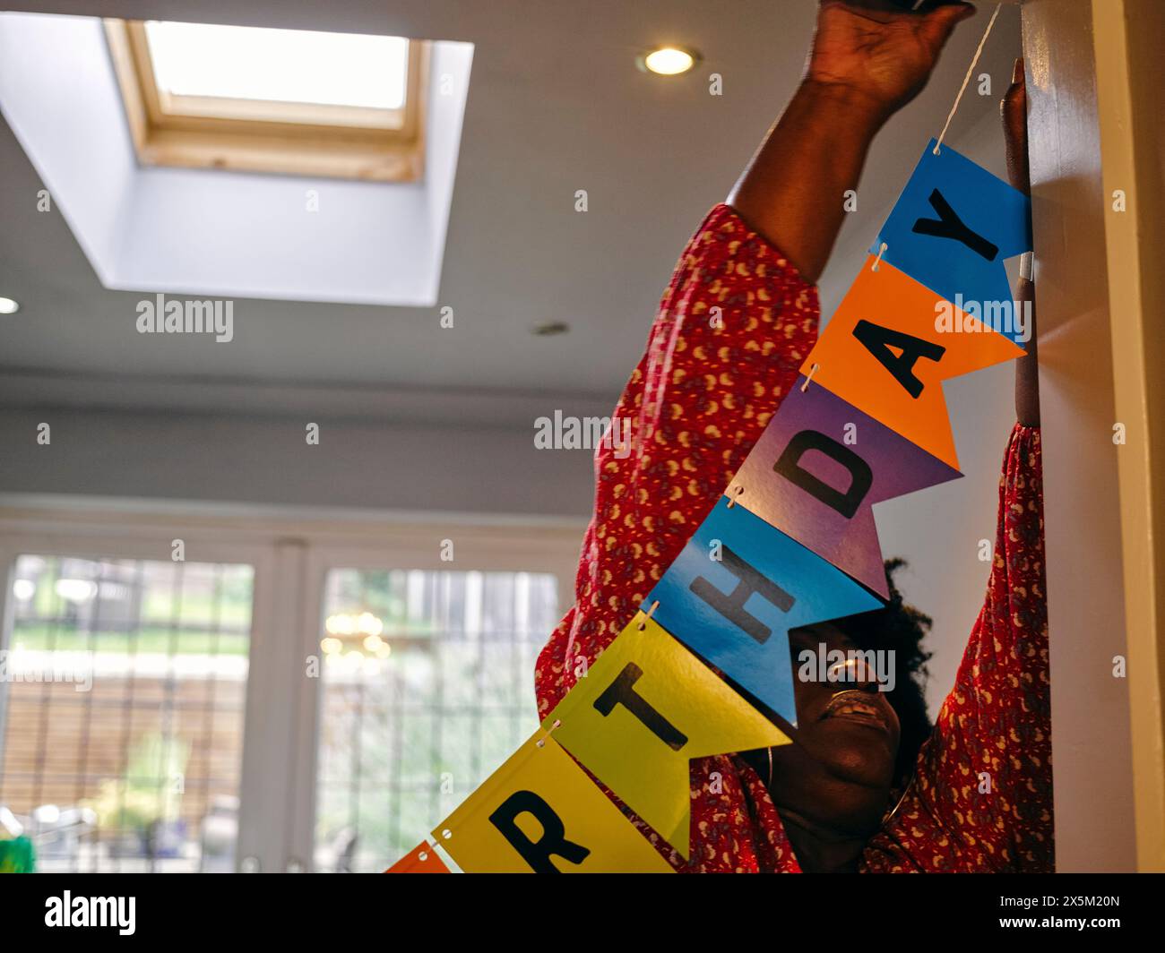 Frau hängt Happy Birthday Banner Stockfoto