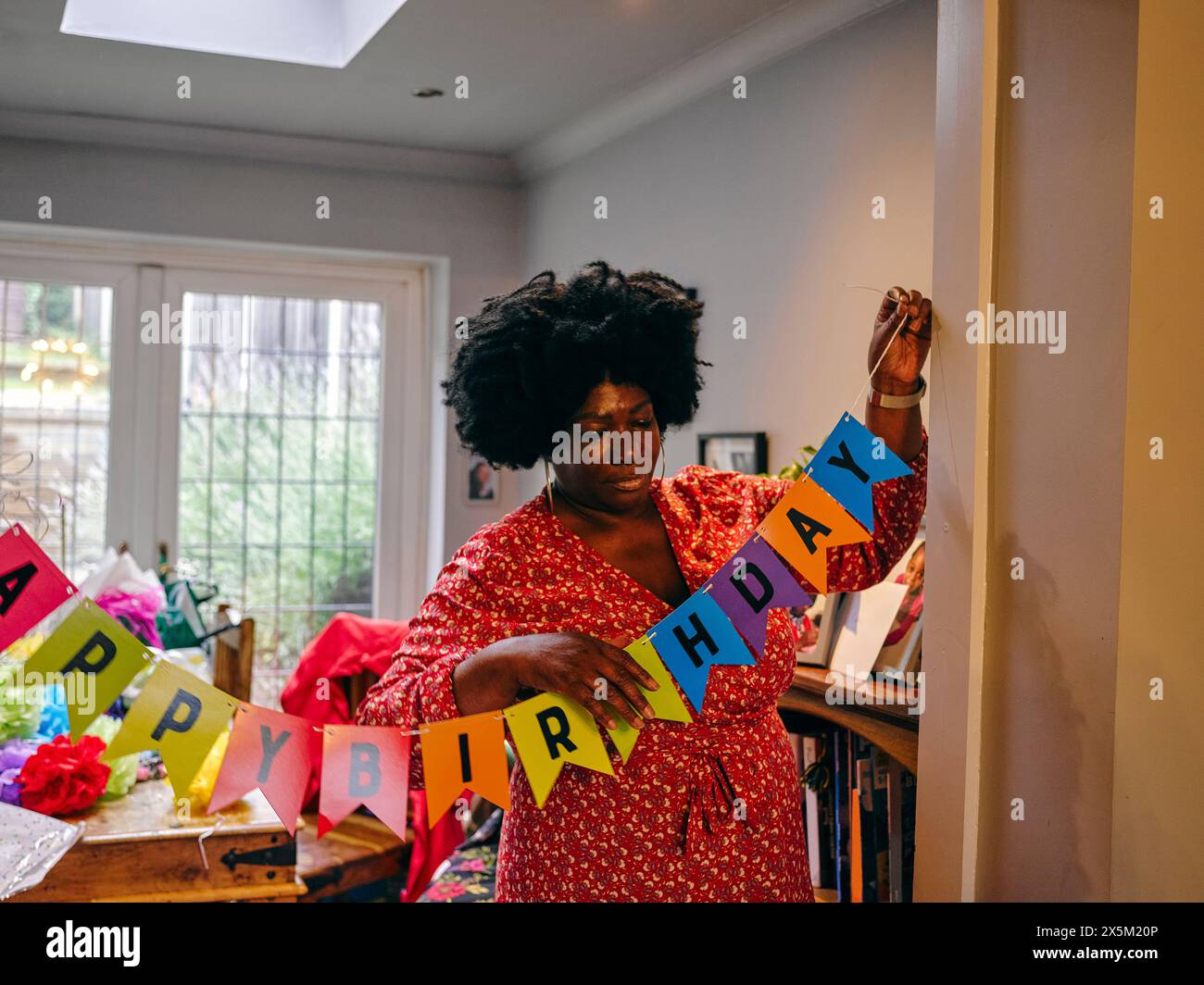 Frau hängt Happy Birthday Banner Stockfoto