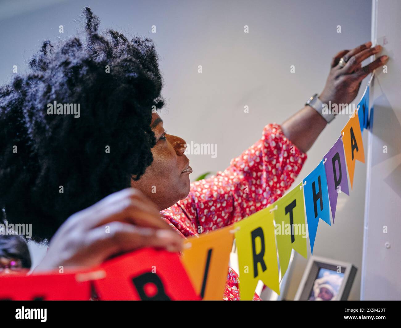 Frau hängt Happy Birthday Banner Stockfoto