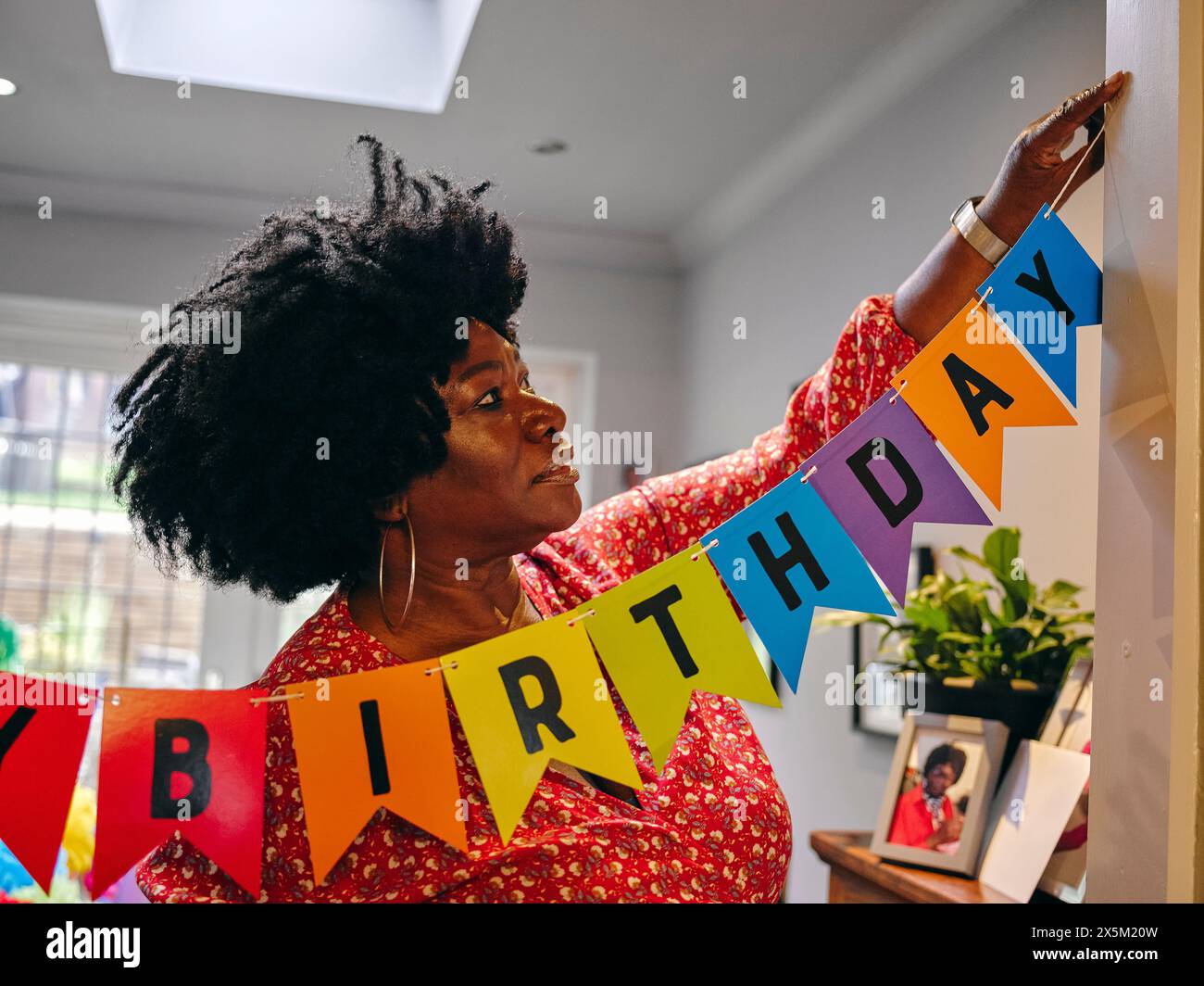Frau hängt Happy Birthday Banner Stockfoto