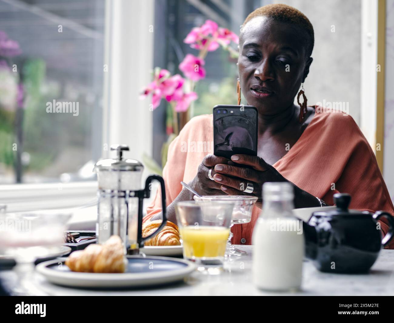 Großbritannien, Frau, die ihr Smartphone am Frühstückstisch im Hotel hält Stockfoto