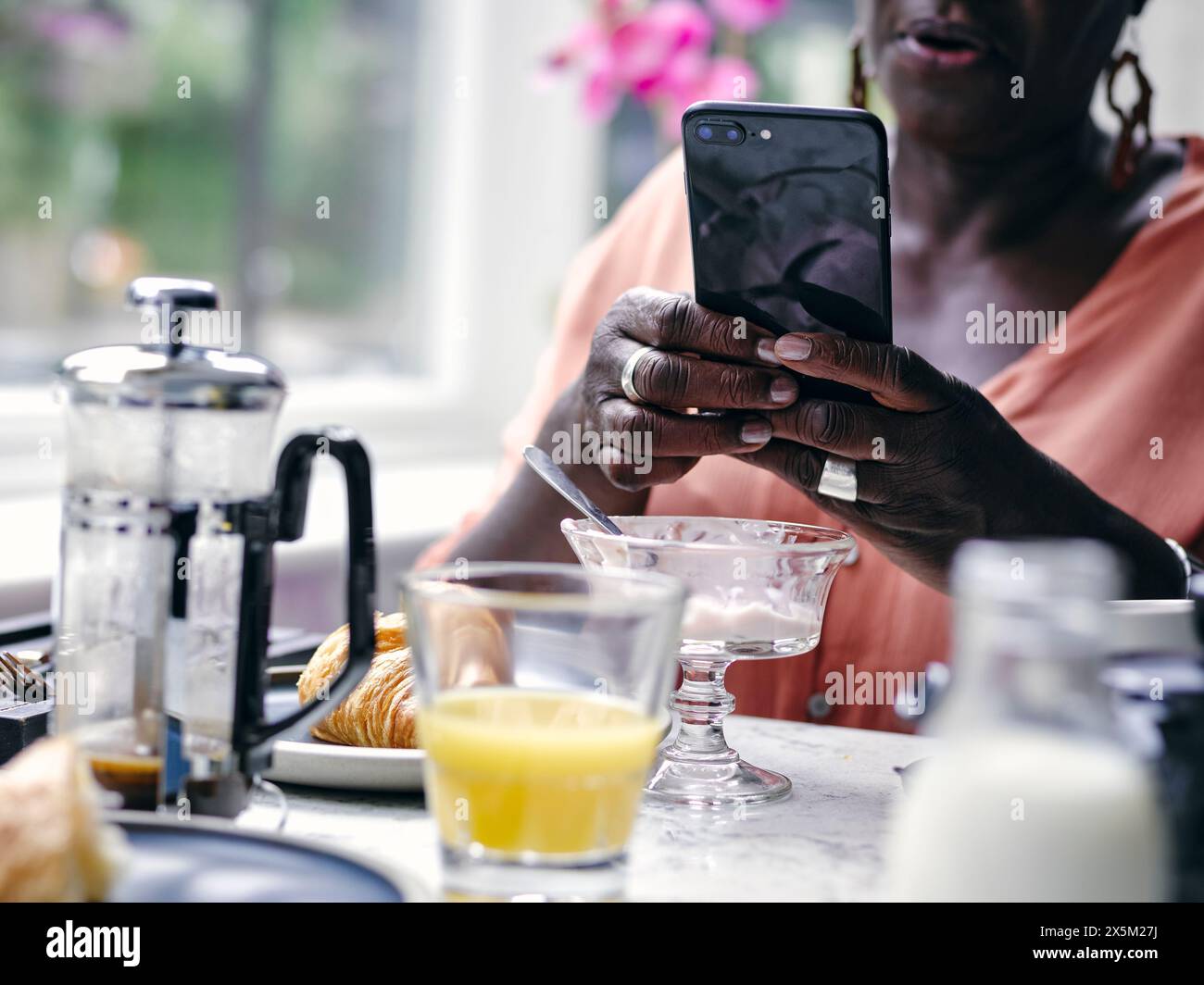 Großbritannien, Nahaufnahme einer Frau, die ihr Smartphone am Frühstückstisch im Hotel hält Stockfoto