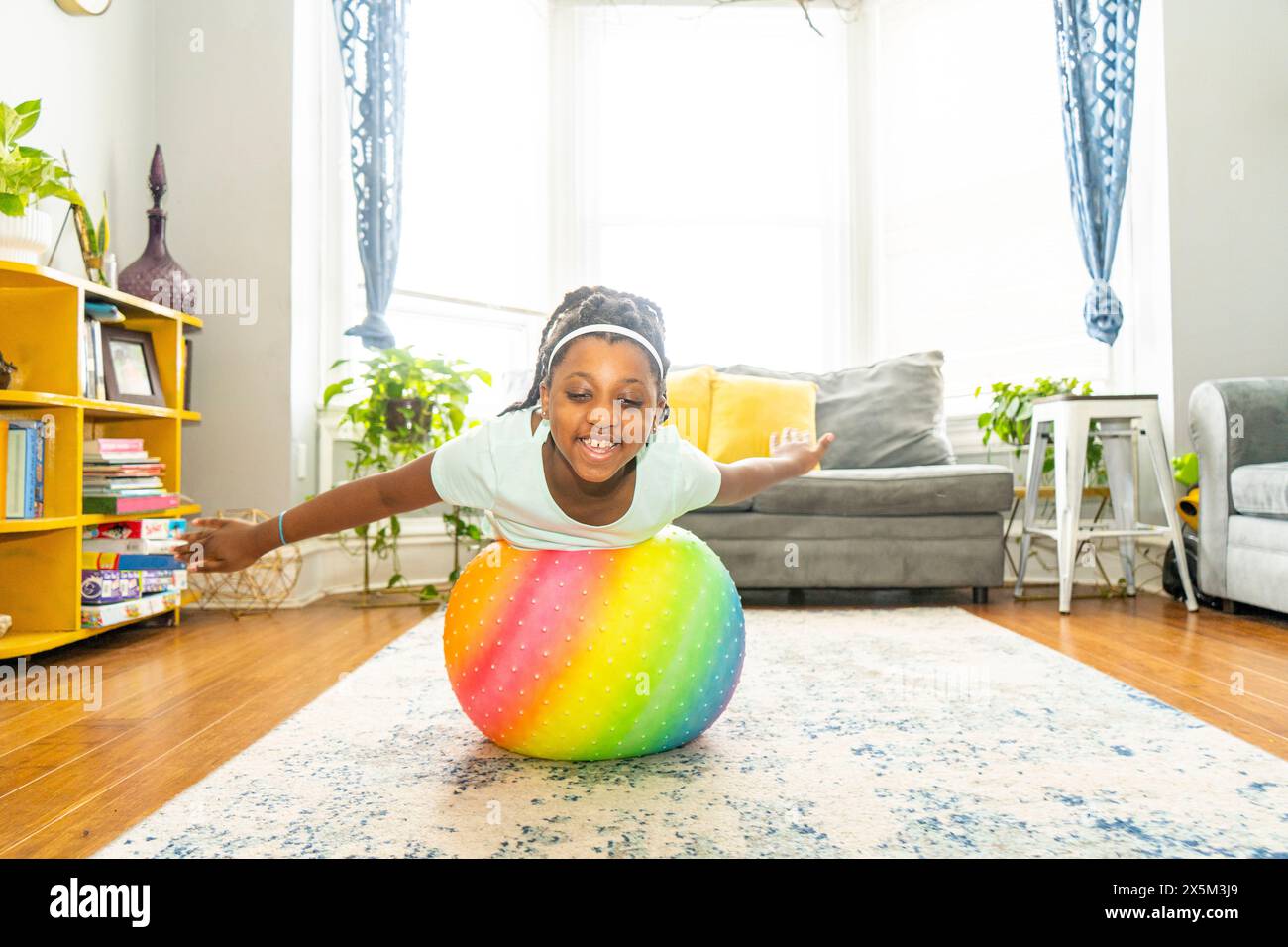 Mädchen, das mit Fitnessball in ihrem Zimmer trainiert Stockfoto
