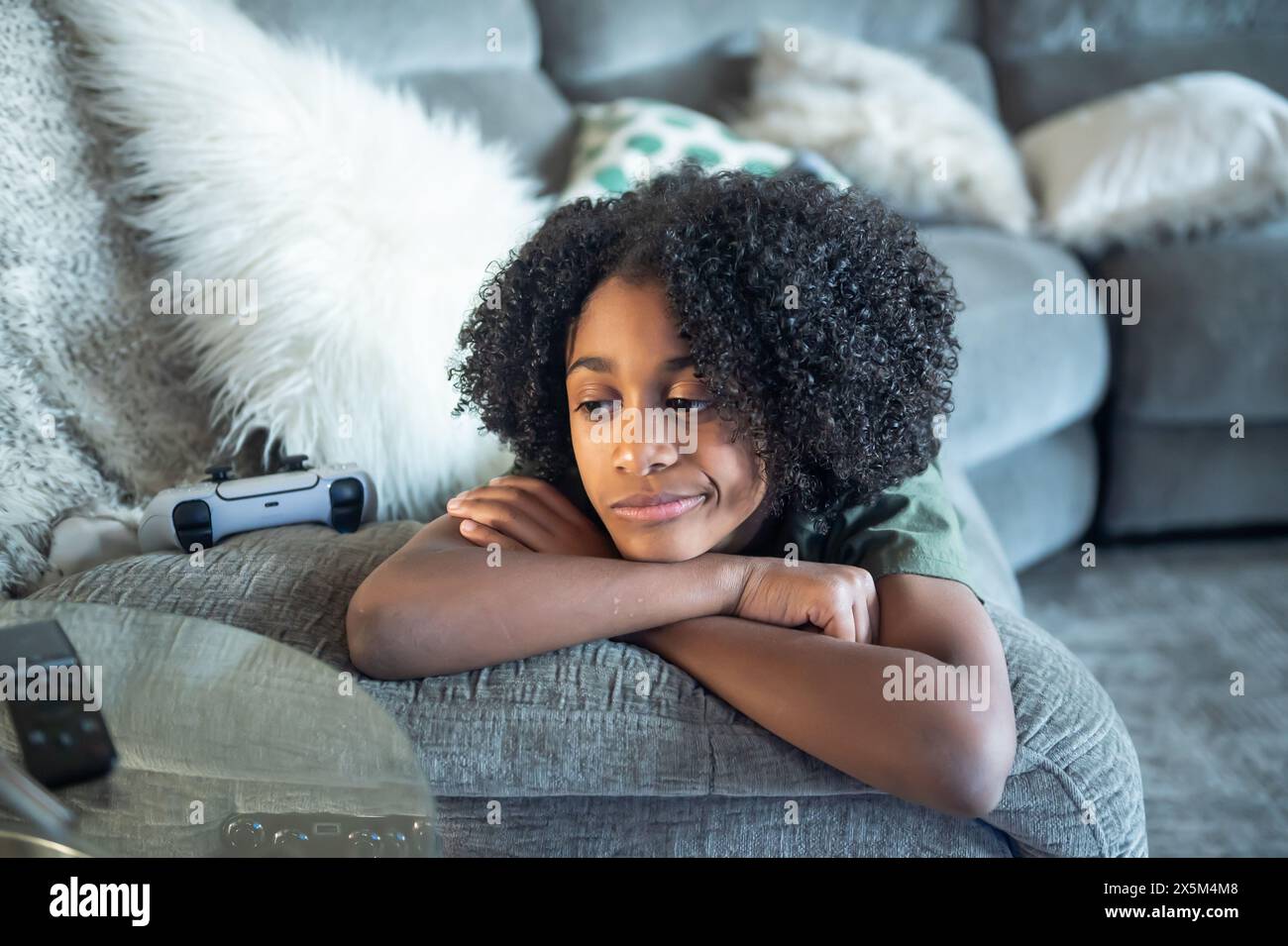Junge, der im Wohnzimmer auf dem Sofa liegt Stockfoto