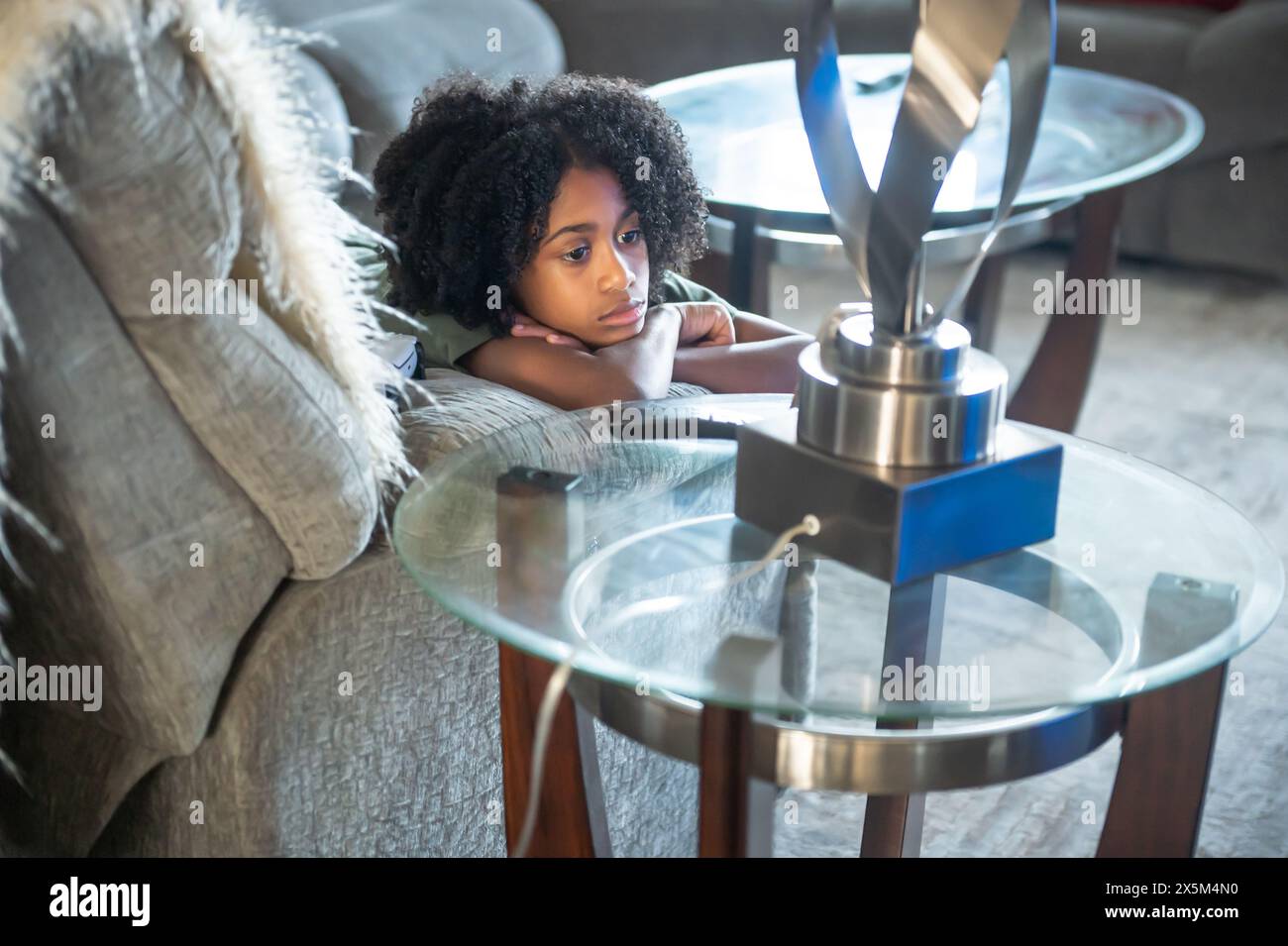 Junge, der im Wohnzimmer auf dem Sofa liegt Stockfoto