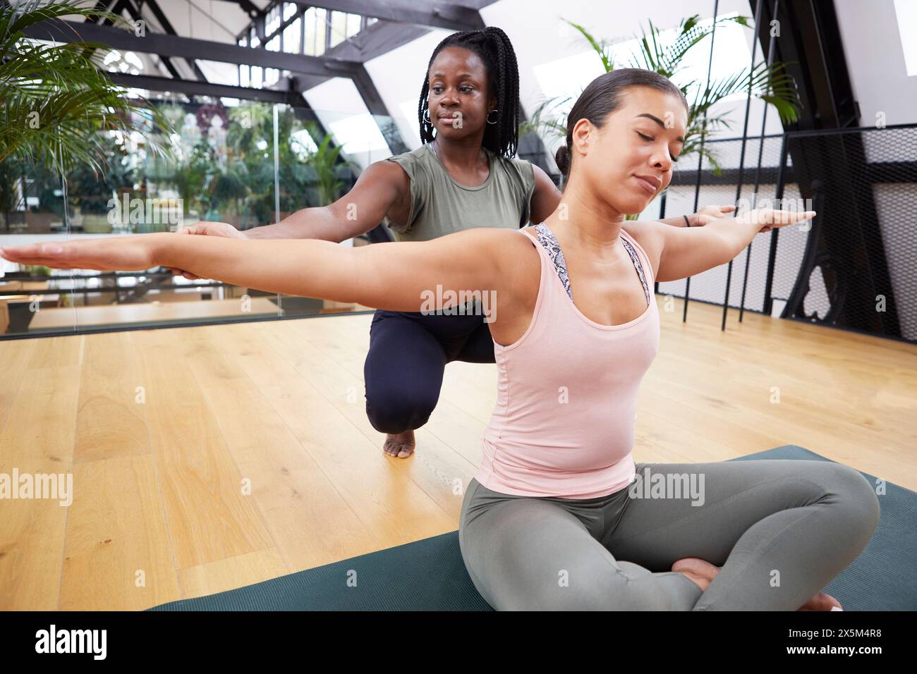 Weibliche Ausbilderin, die einer Frau beim Pilates im Studio hilft Stockfoto