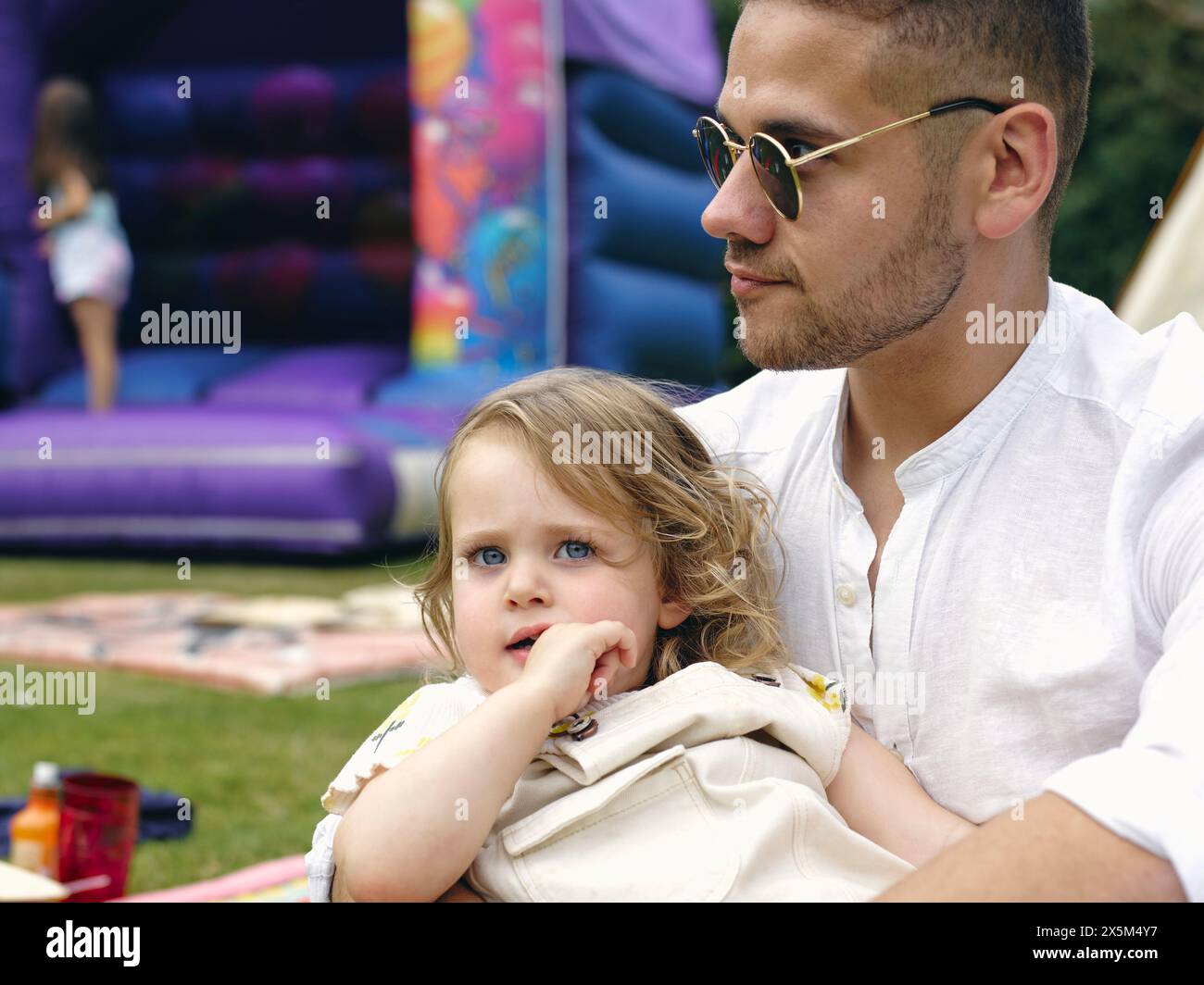 Vater hält Tochter auf einer Party im Freien Stockfoto