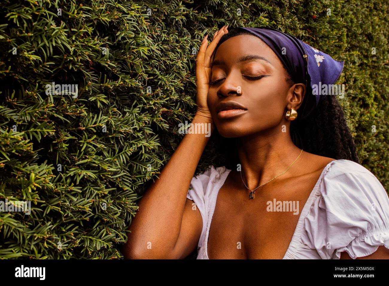 Porträt einer jungen Frau, die sich auf Evergreens stützt Stockfoto
