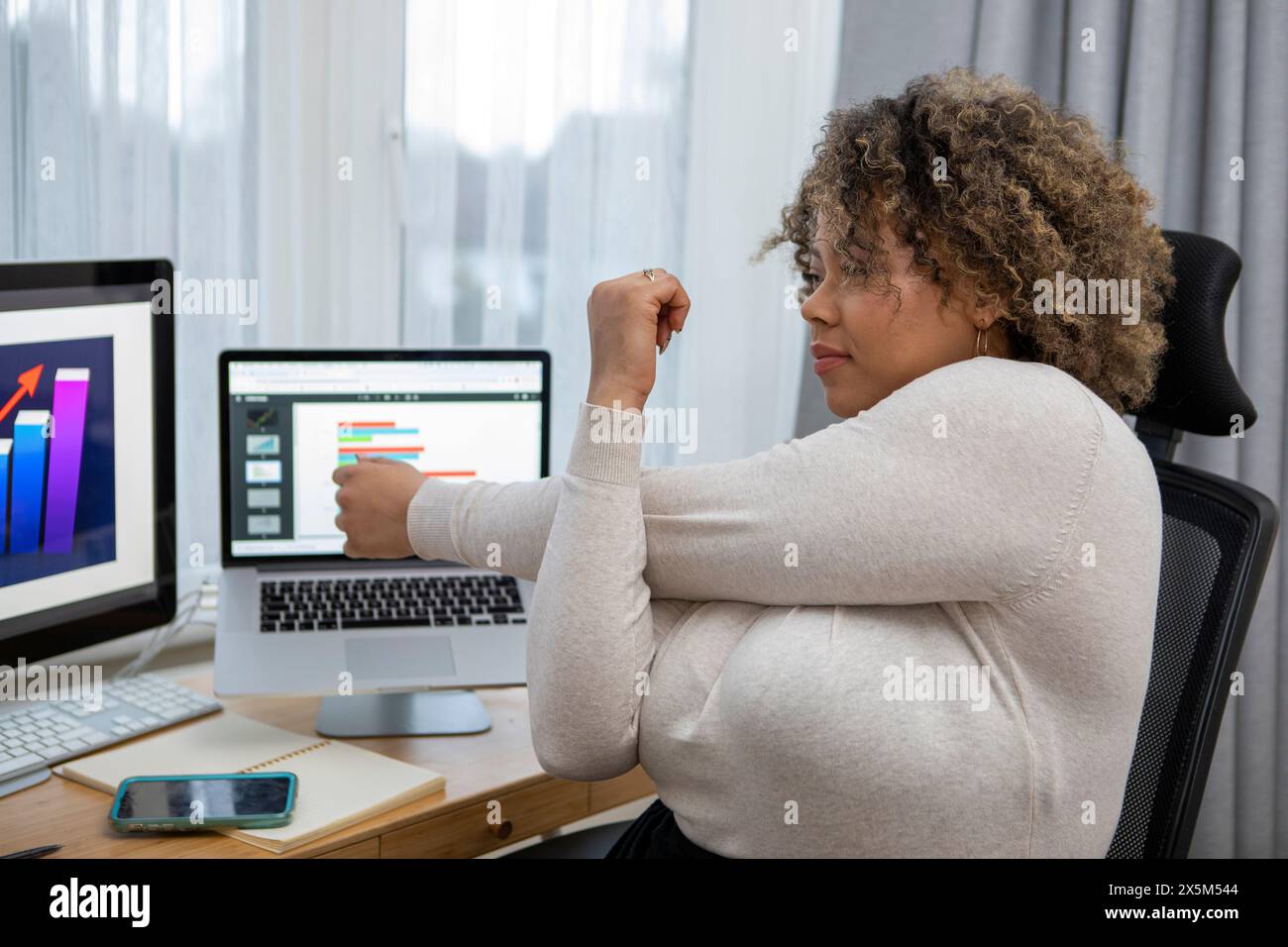 Frau, die sich am Schreibtisch im Home Office ausdehnt Stockfoto