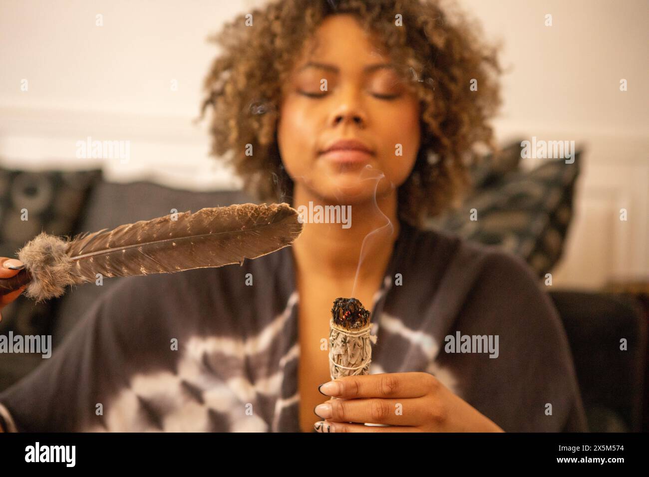 Frau, die schwelenden weißen Salbei und Feder hält Stockfoto