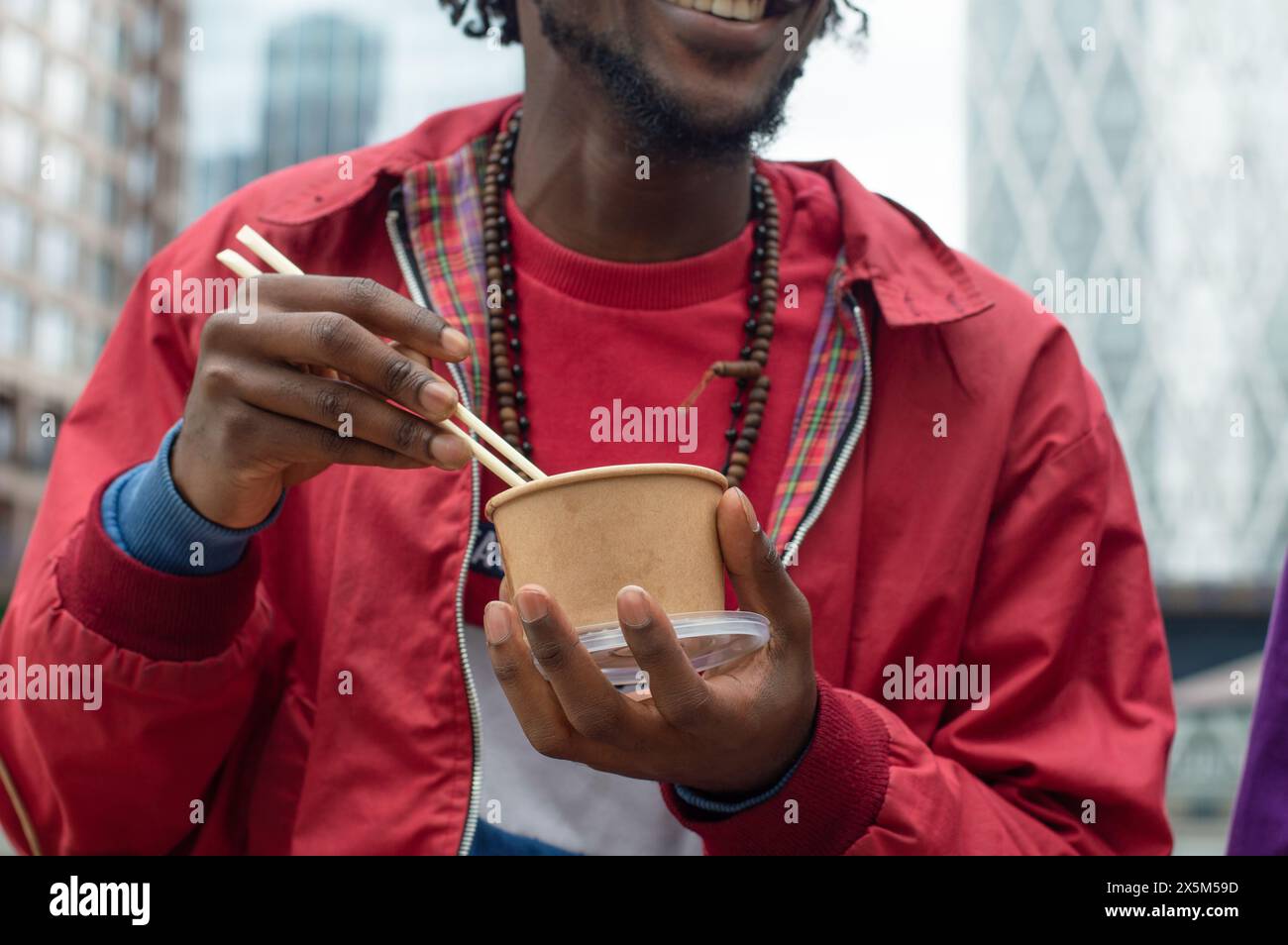 Der mittlere Teil des Mannes, der asiatische Essen in der Stadt isst Stockfoto