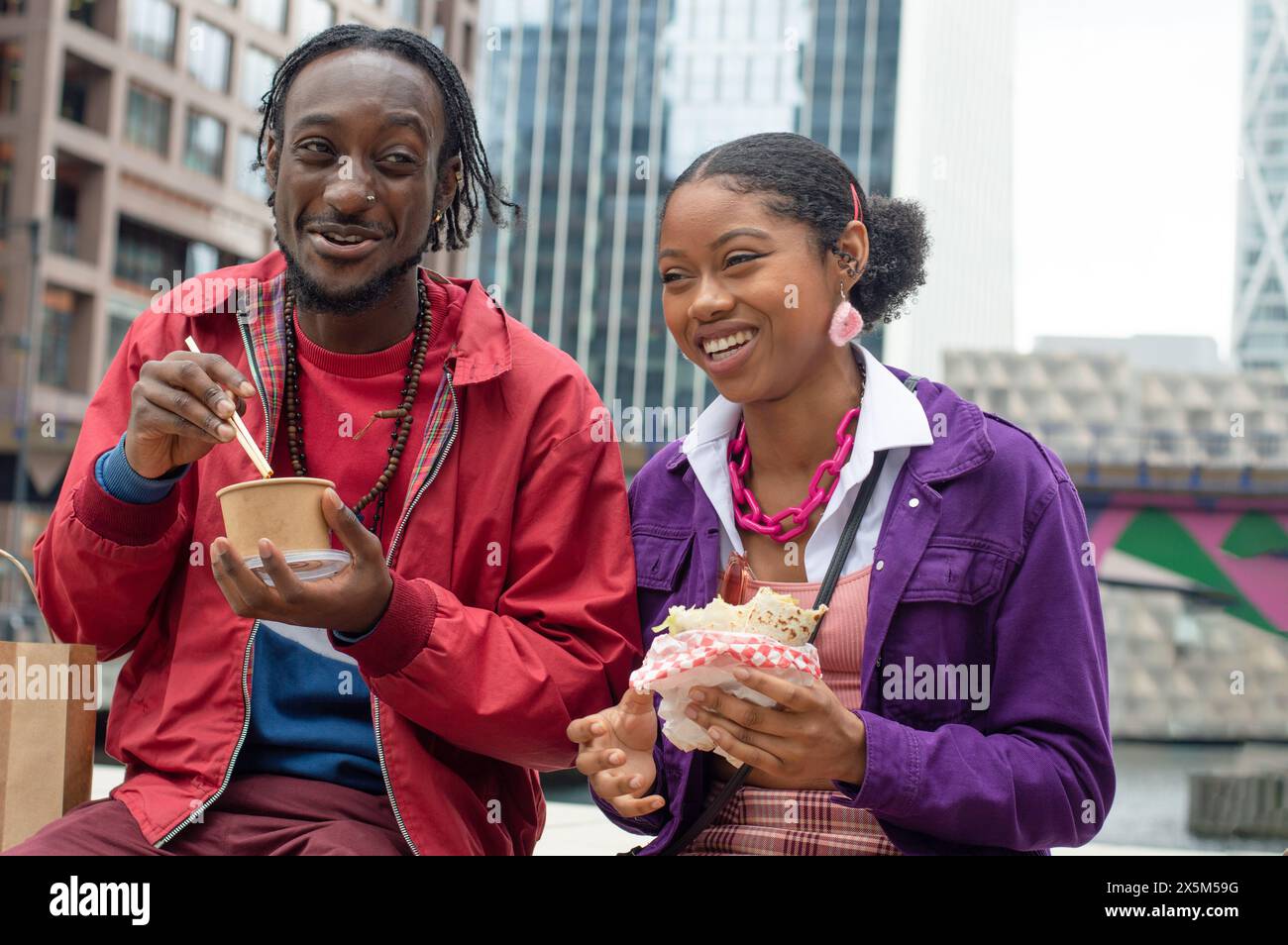 Lächelnde Freunde essen Essen in der Stadt Stockfoto