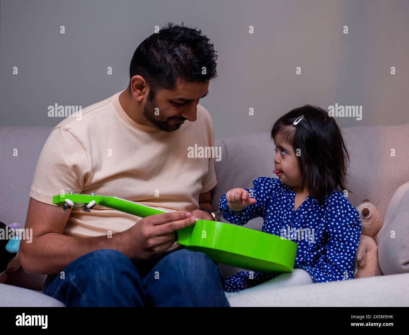 Vater spielt mit Spielzeuggitarre mit Tochter Stockfoto