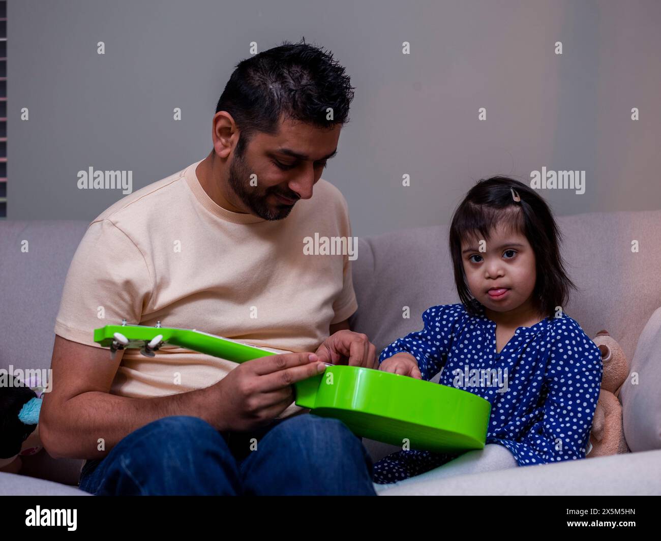 Vater spielt mit Spielzeuggitarre mit Tochter Stockfoto
