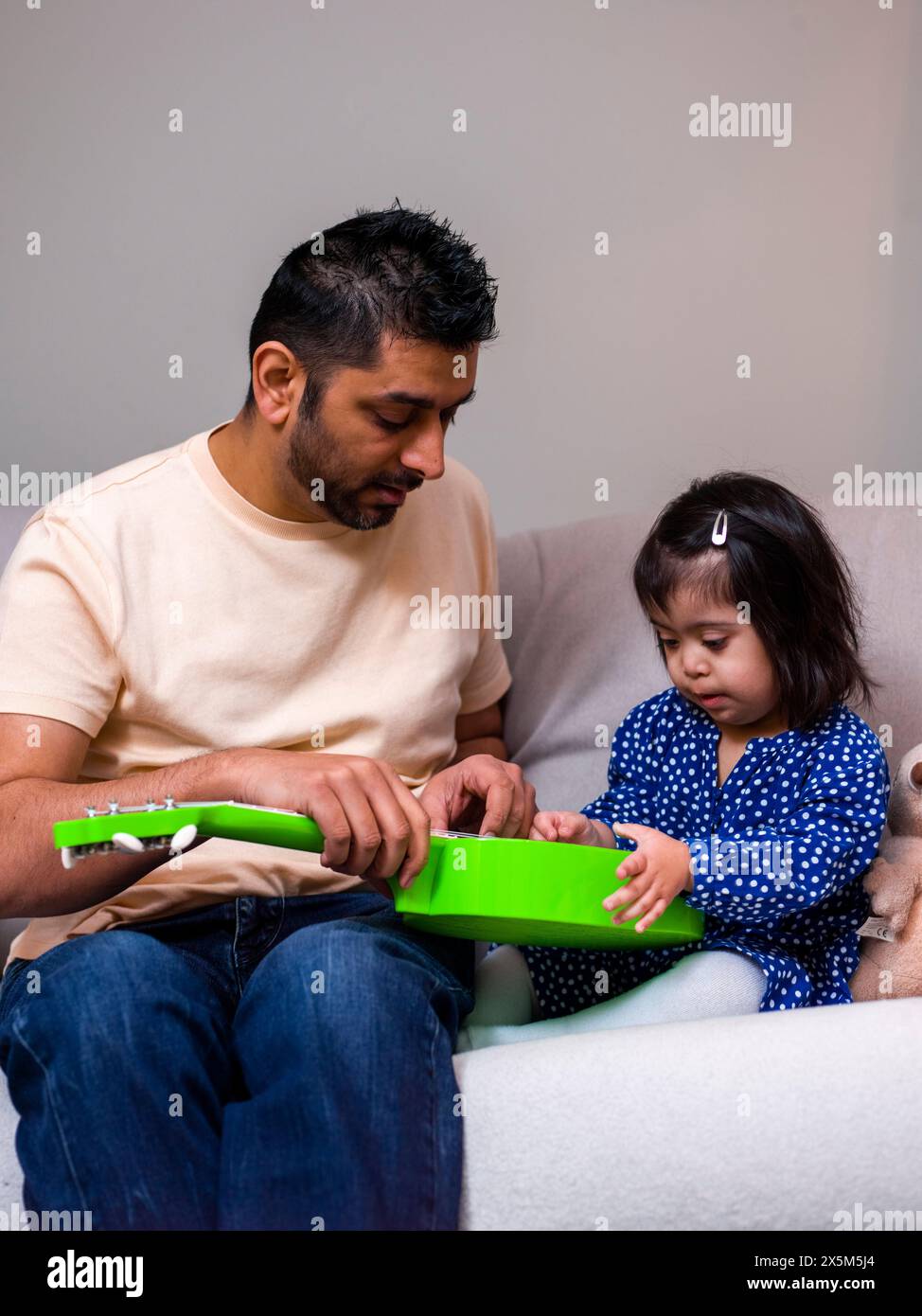 Vater spielt mit Spielzeuggitarre mit Tochter Stockfoto