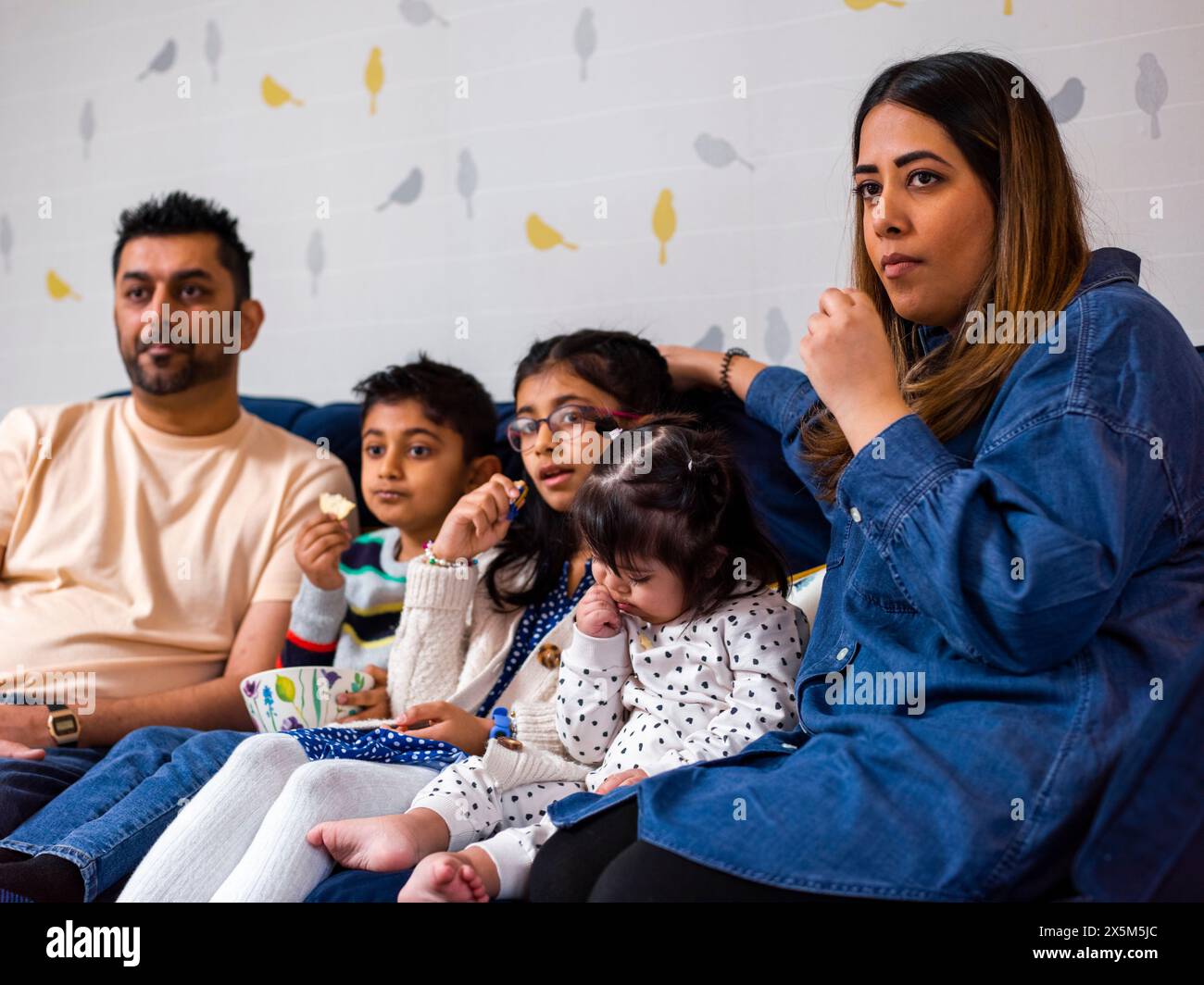 Eltern mit Kindern sitzen auf dem Sofa und schauen fern Stockfoto
