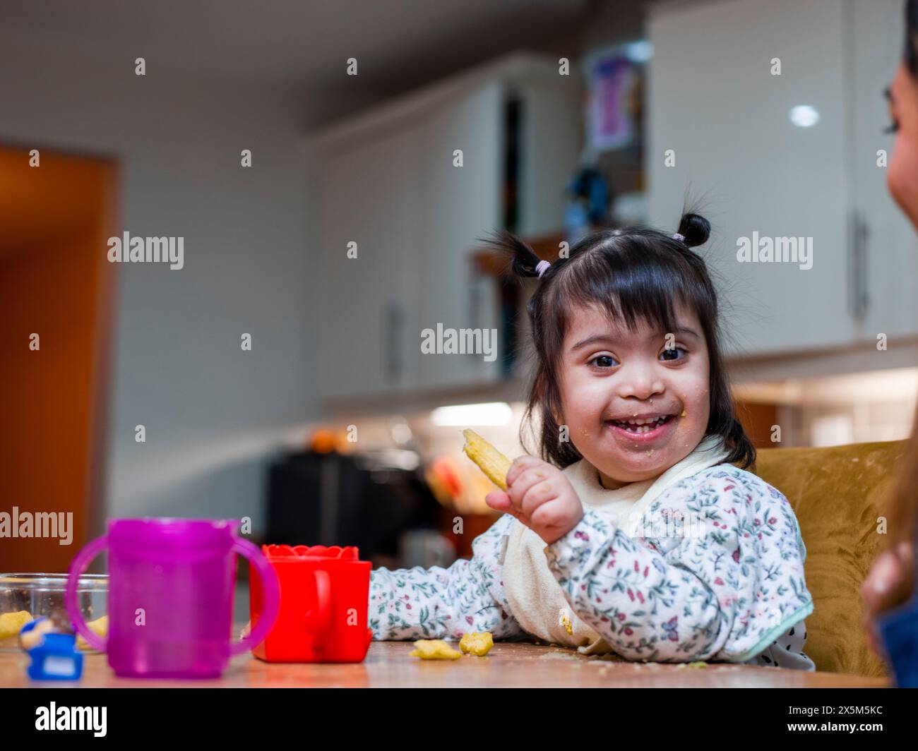 Porträt eines Mädchens mit Down-Syndrom beim Essen am Tisch Stockfoto
