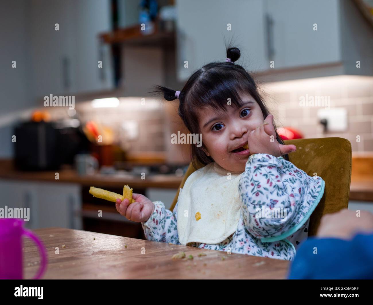 Porträt eines Mädchens mit Down-Syndrom beim Essen am Tisch Stockfoto