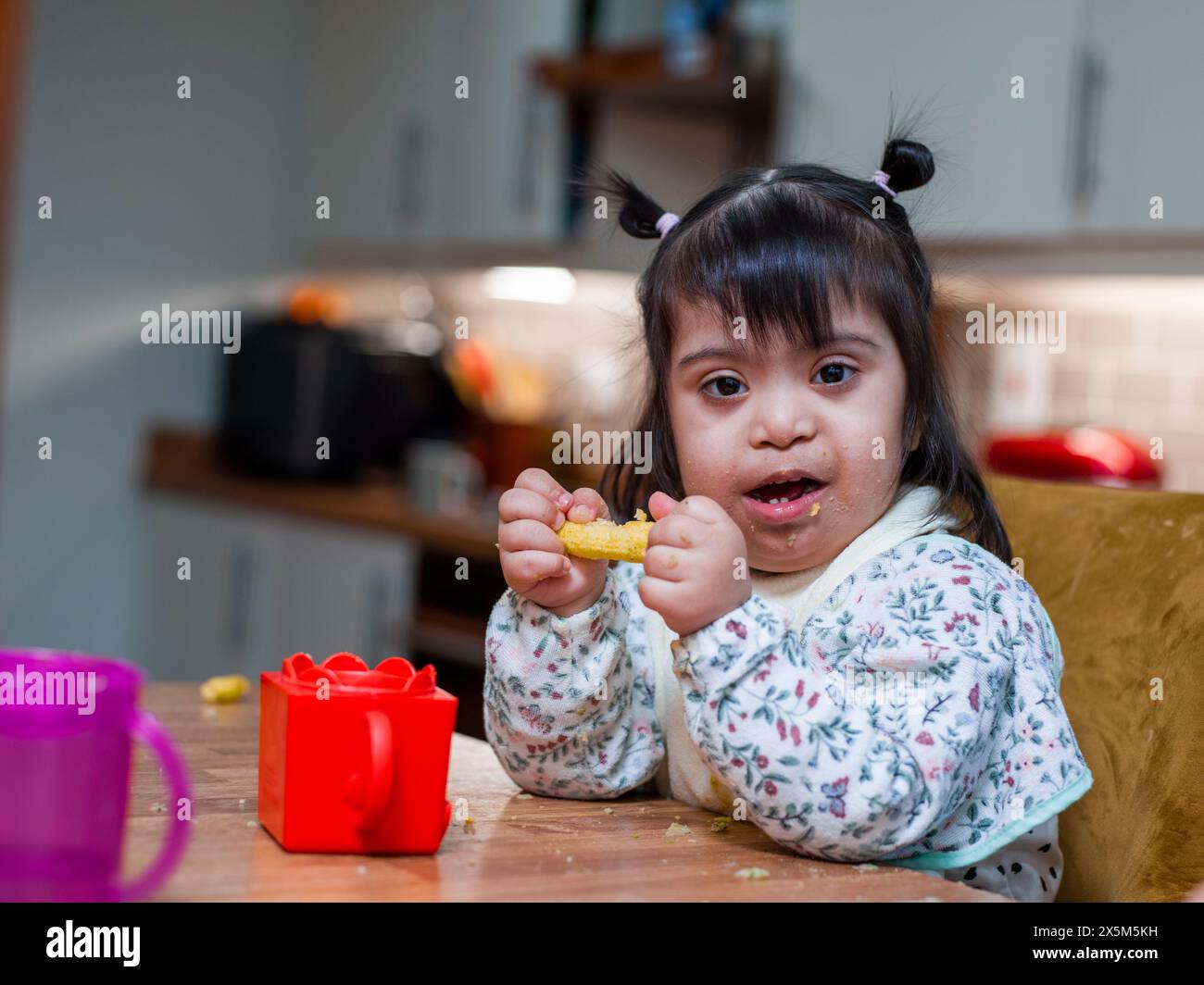 Porträt eines Mädchens mit Down-Syndrom beim Essen am Tisch Stockfoto