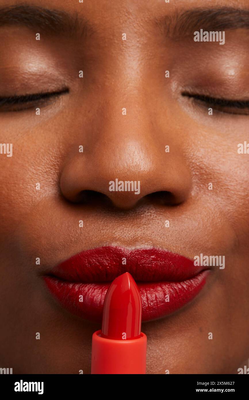 Nahaufnahme einer Frau, die roten Lippenstift aufträgt Stockfoto