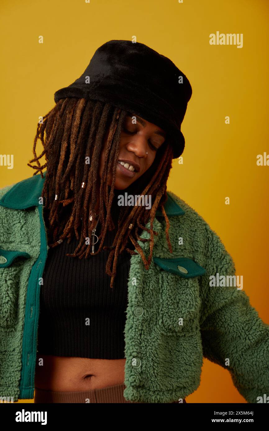 Studio-Porträt einer Frau mit Hut auf gelbem Hintergrund Stockfoto