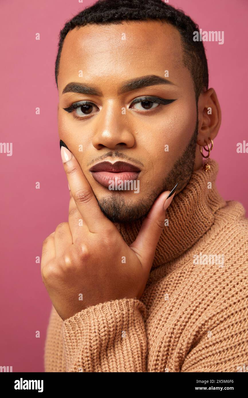 Studio-Porträt eines queeren Mannes vor violettem Hintergrund Stockfoto