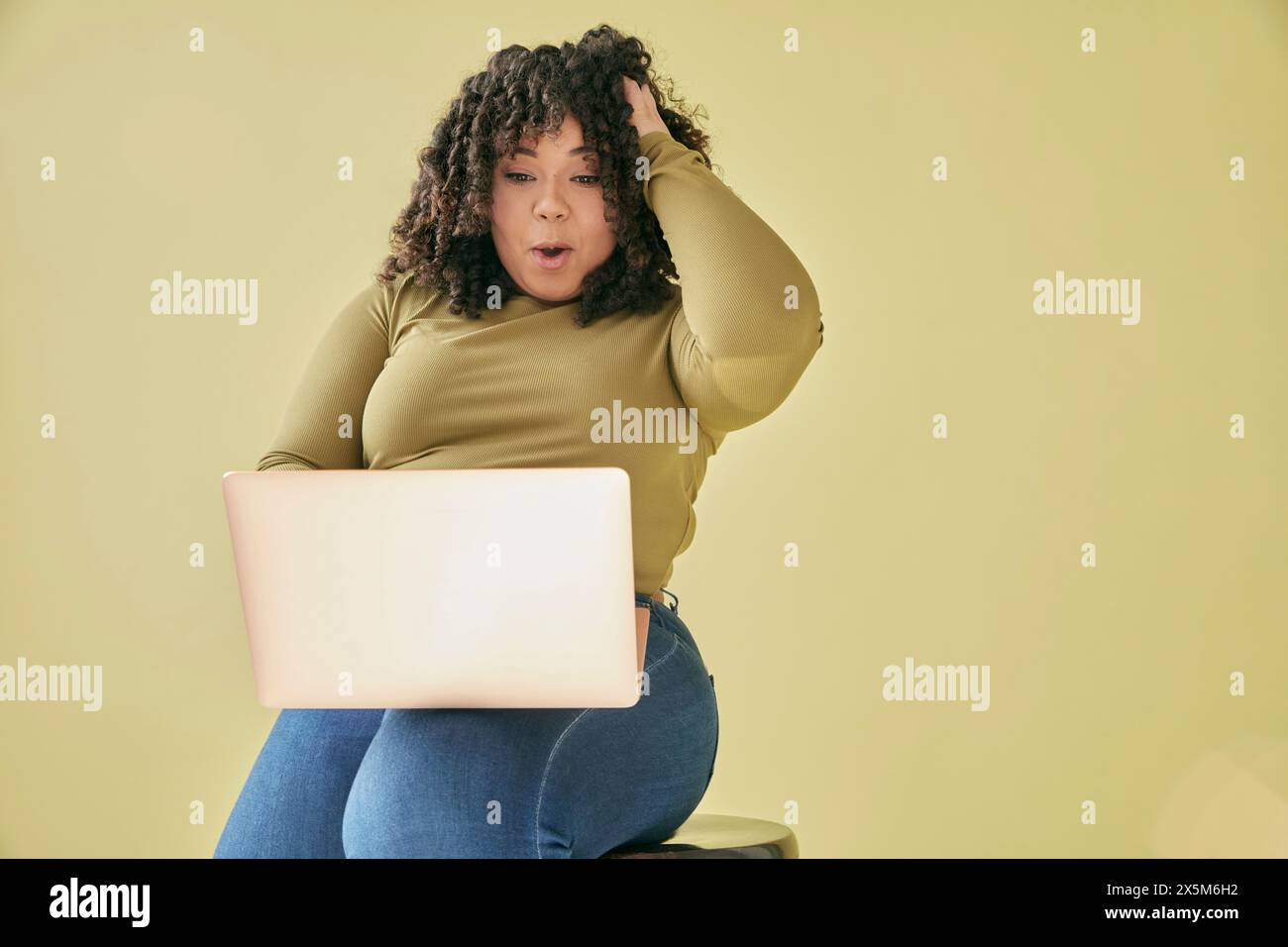 Studio-Aufnahme einer überraschten jungen Frau, die auf Laptop aussieht Stockfoto