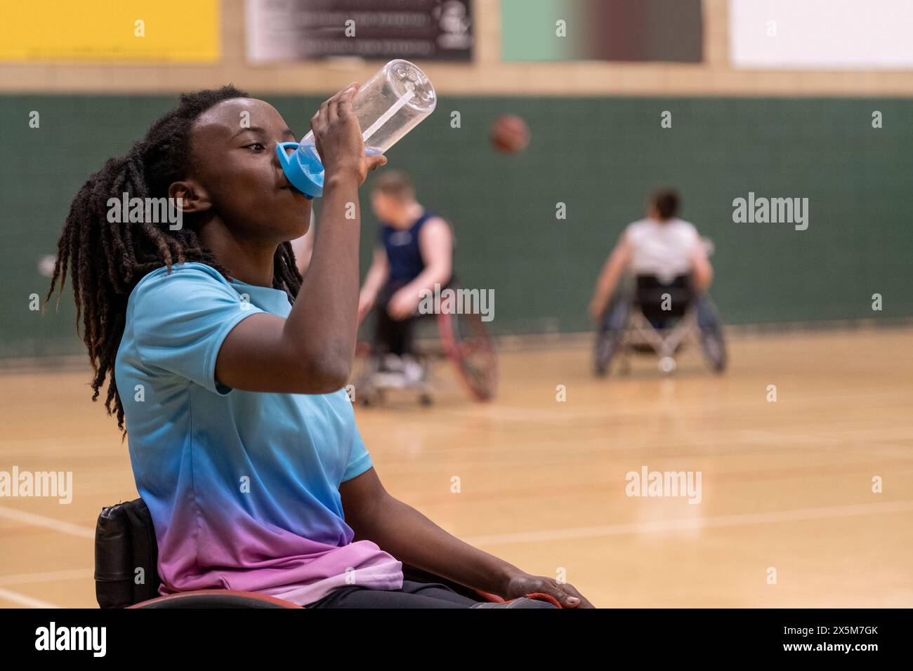 Teenager-Mädchen im Rollstuhl, die beim Basketballspiel eine Wasserpause hat Stockfoto