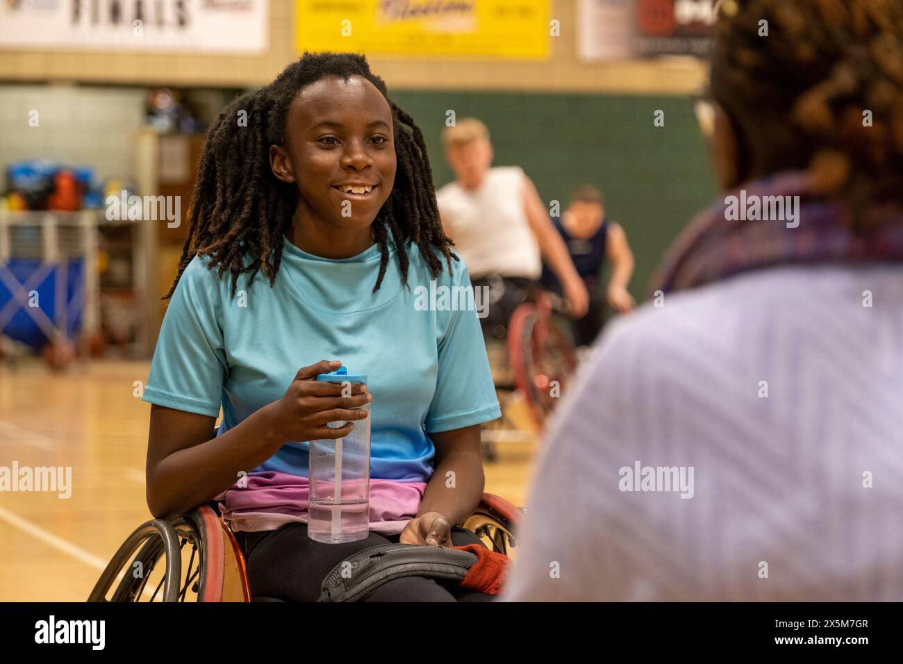 Teenager-Mädchen im Rollstuhl, die beim Basketballspiel eine Wasserpause hat Stockfoto