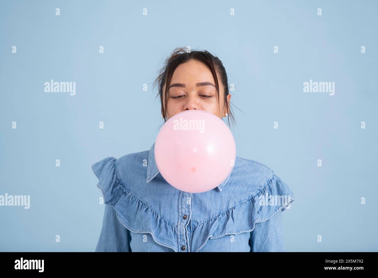 Studio-Aufnahme einer jungen Frau, die Kaugummi kaut und Blase bläst Stockfoto