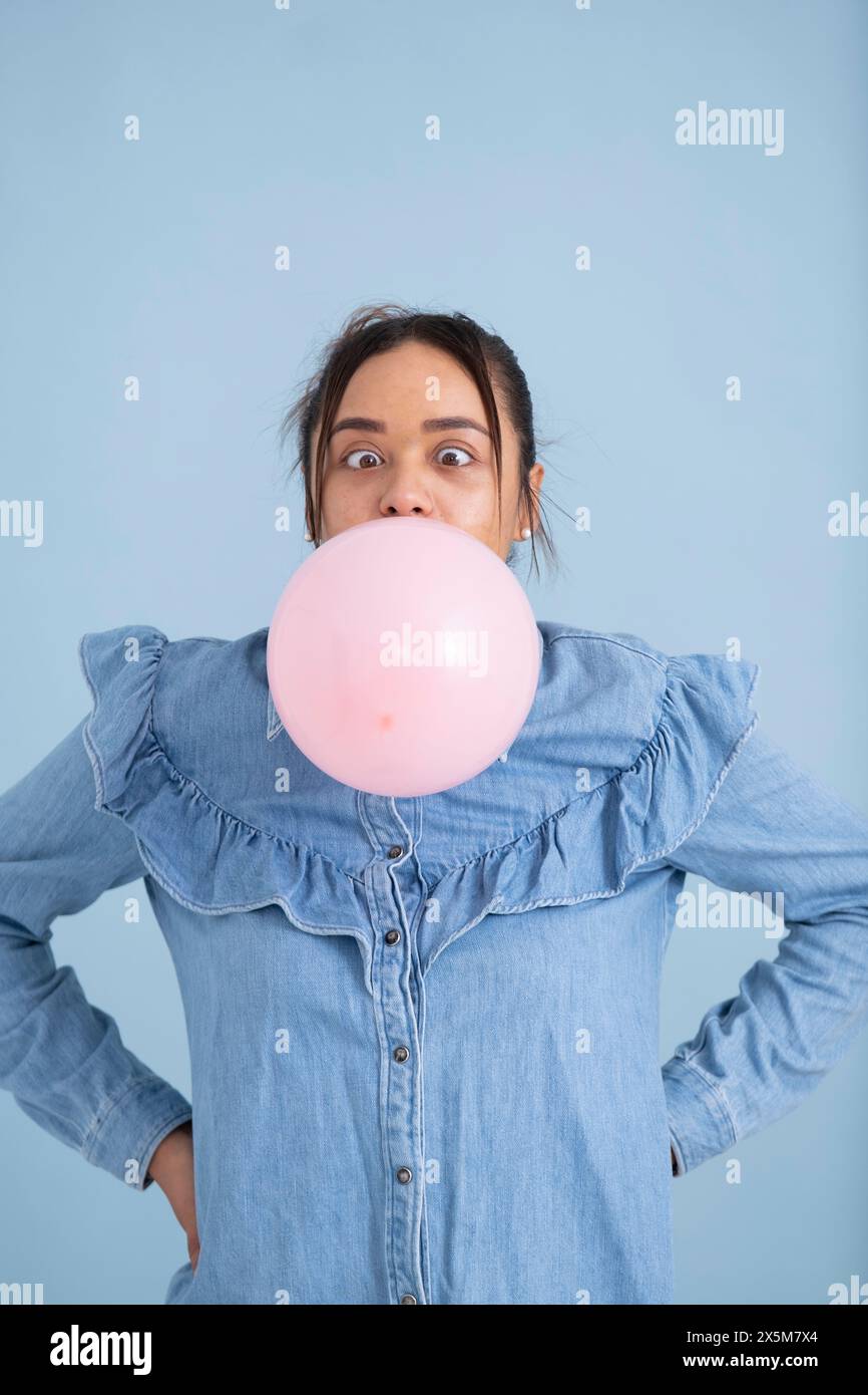 Atelierporträt einer jungen Frau, die Kaugummi kaut und Blase bläst Stockfoto