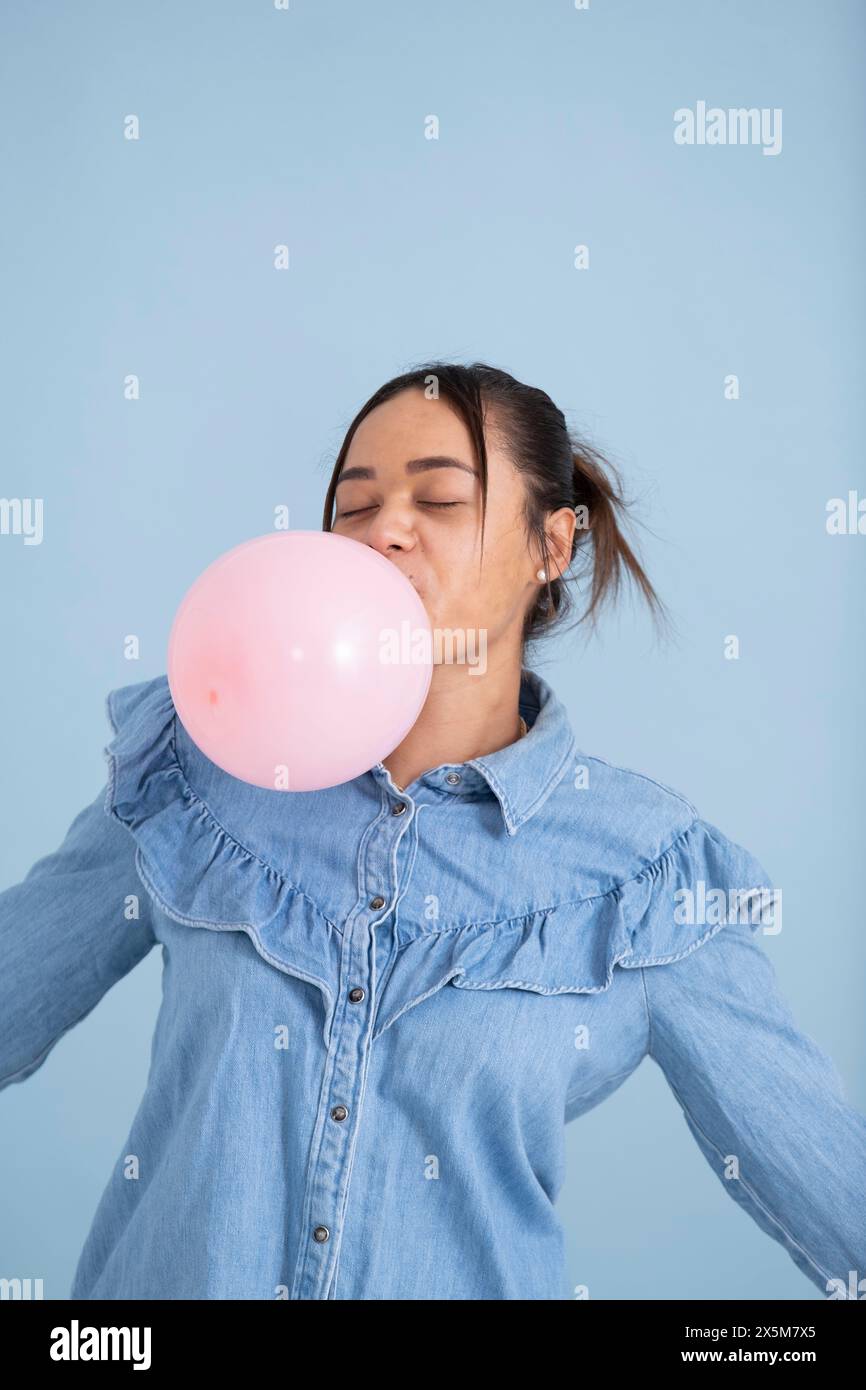 Studio-Aufnahme einer jungen Frau, die Kaugummi kaut und Blase bläst Stockfoto
