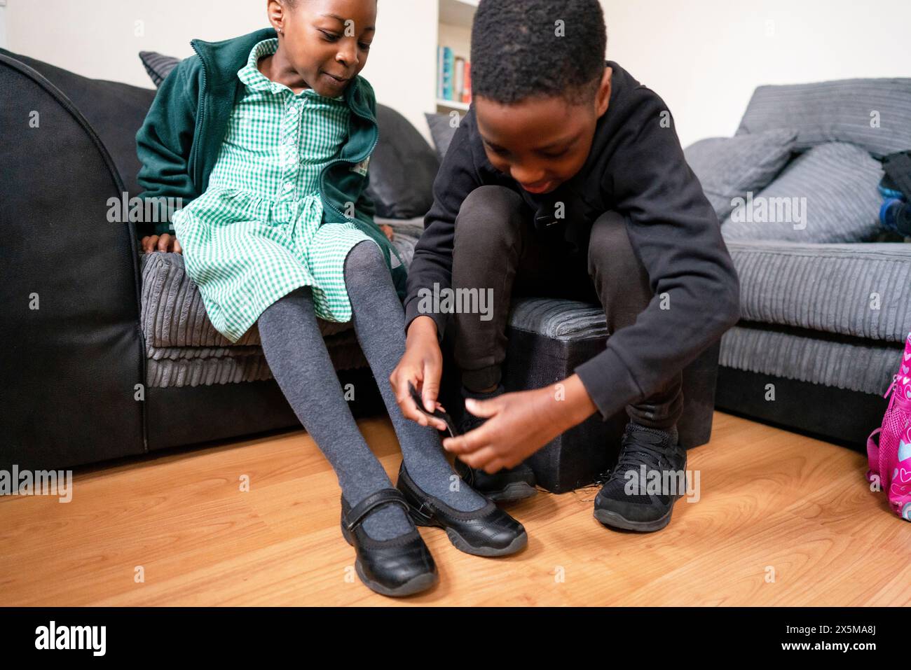 Bruder hilft Schwester, Schuhe anzuziehen Stockfoto