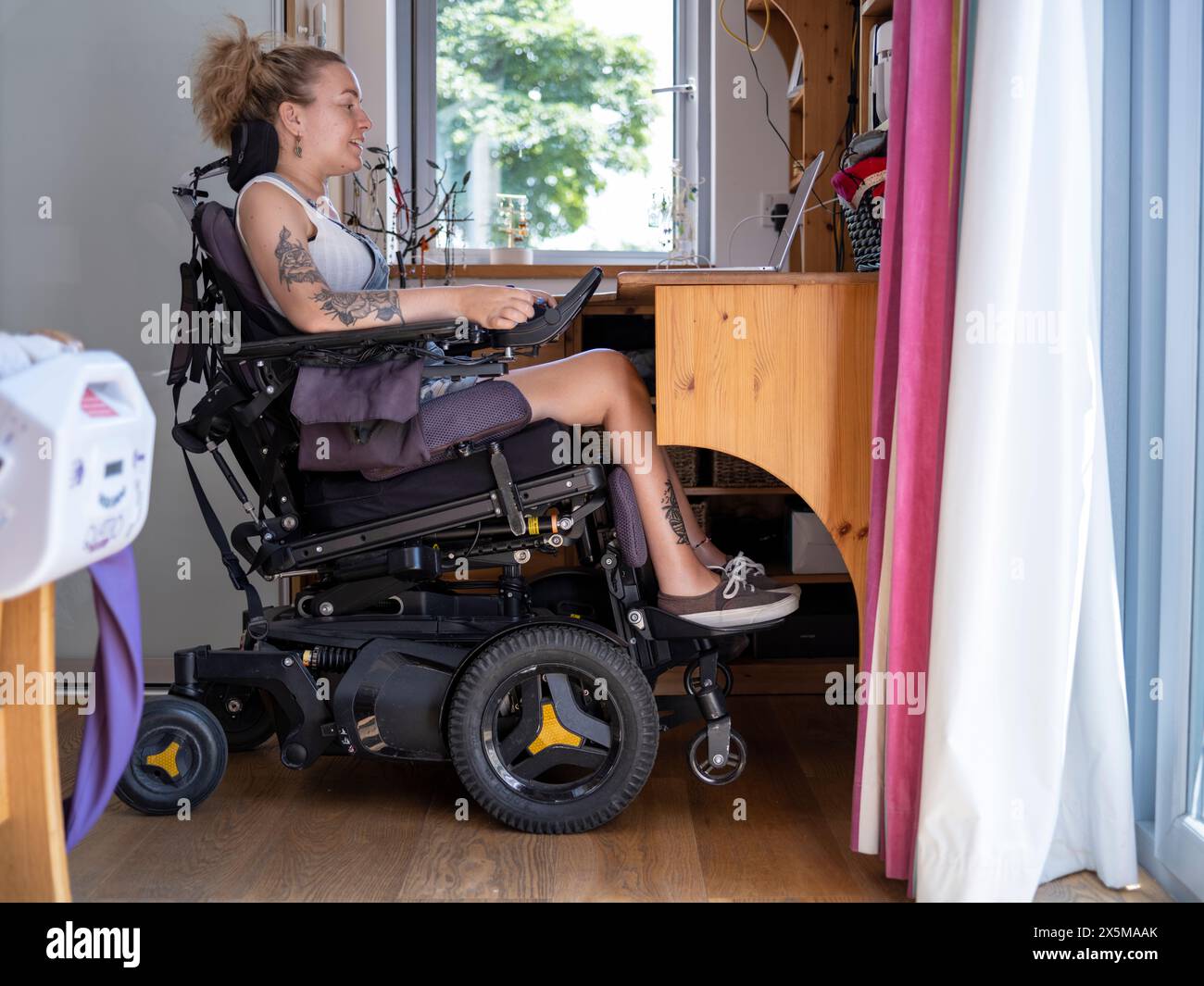 Frau im elektrischen Rollstuhl, die an einem Laptop arbeitet Stockfoto