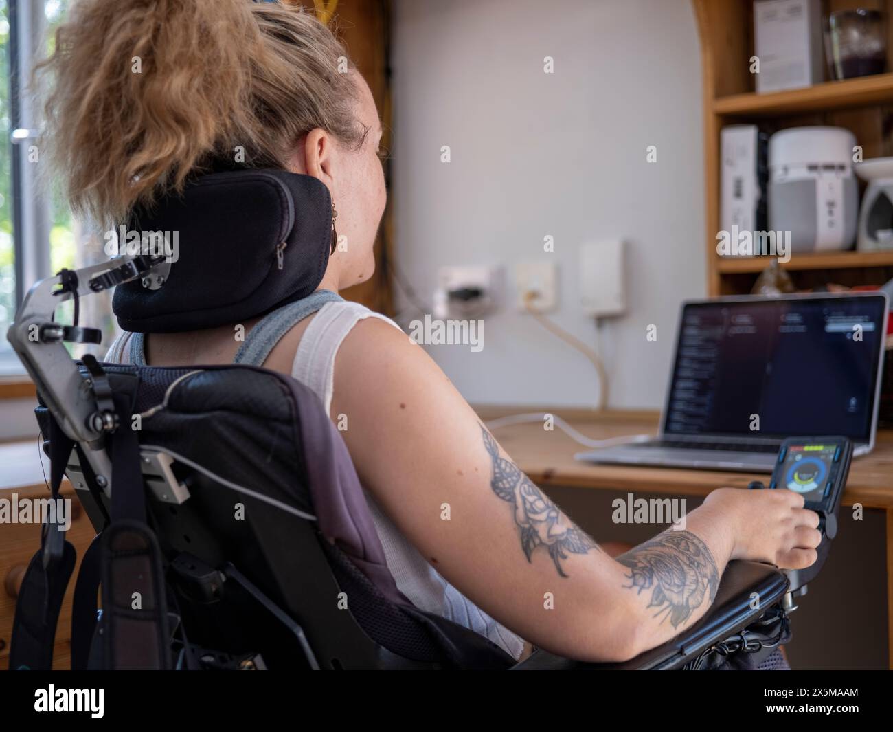 Frau im elektrischen Rollstuhl, die an einem Laptop arbeitet Stockfoto