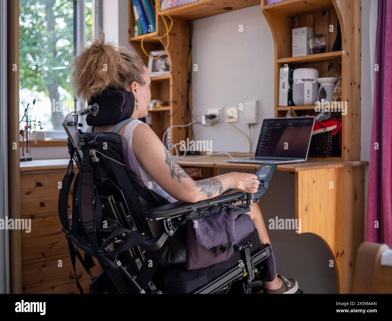 Frau im elektrischen Rollstuhl, die an einem Laptop arbeitet Stockfoto