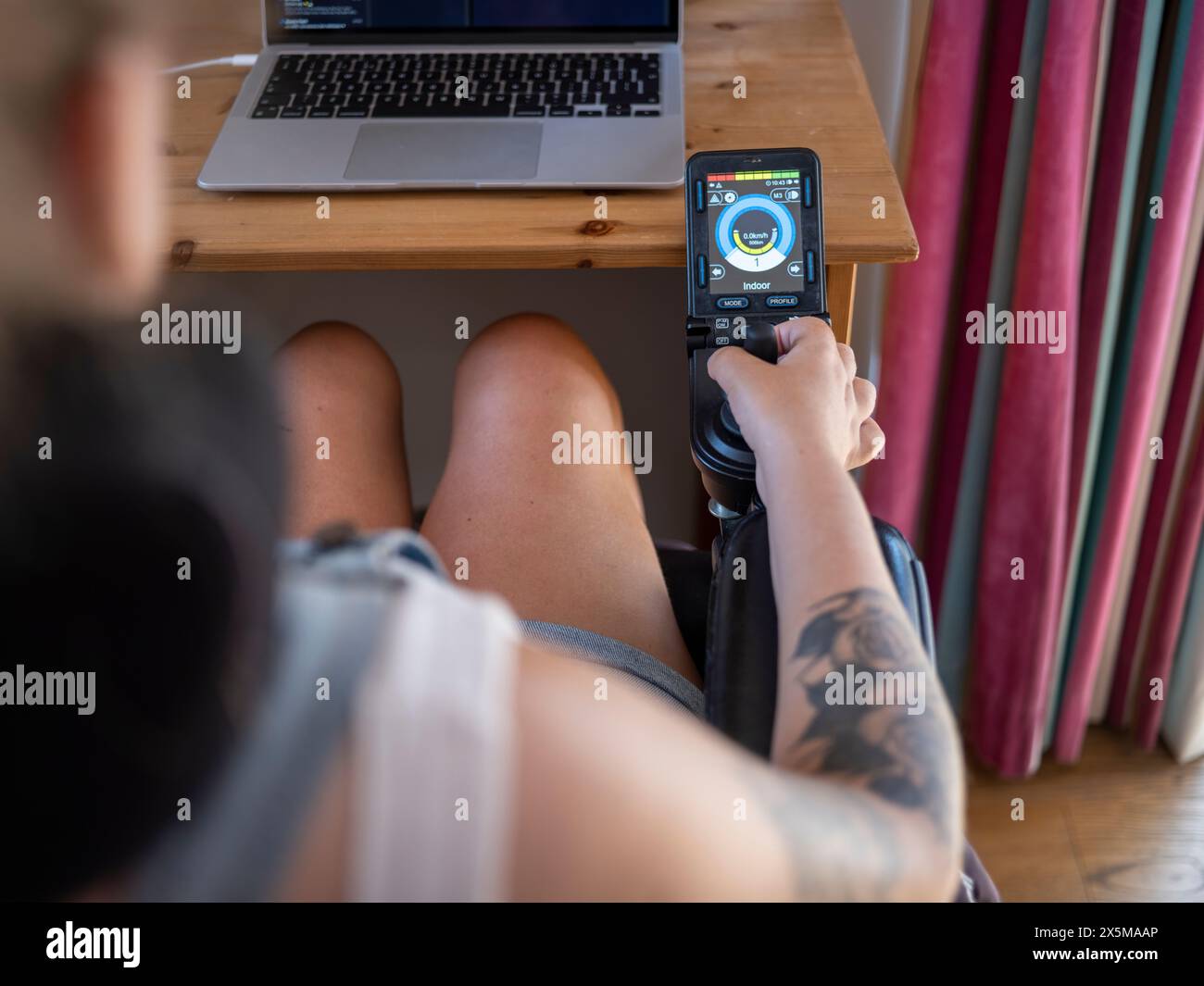 Frau im elektrischen Rollstuhl mit Joystick mit Bildschirm Stockfoto