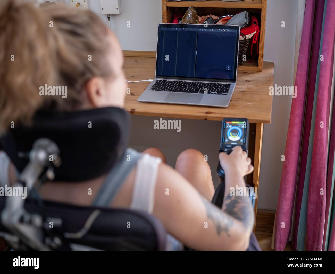 Frau im elektrischen Rollstuhl, die an einem Laptop arbeitet Stockfoto