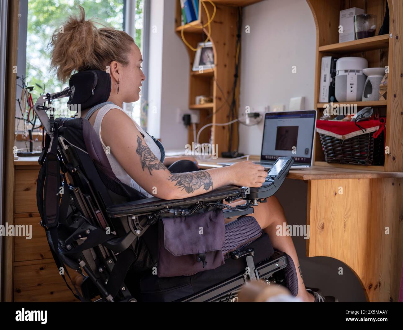 Frau im elektrischen Rollstuhl, die an einem Laptop arbeitet Stockfoto