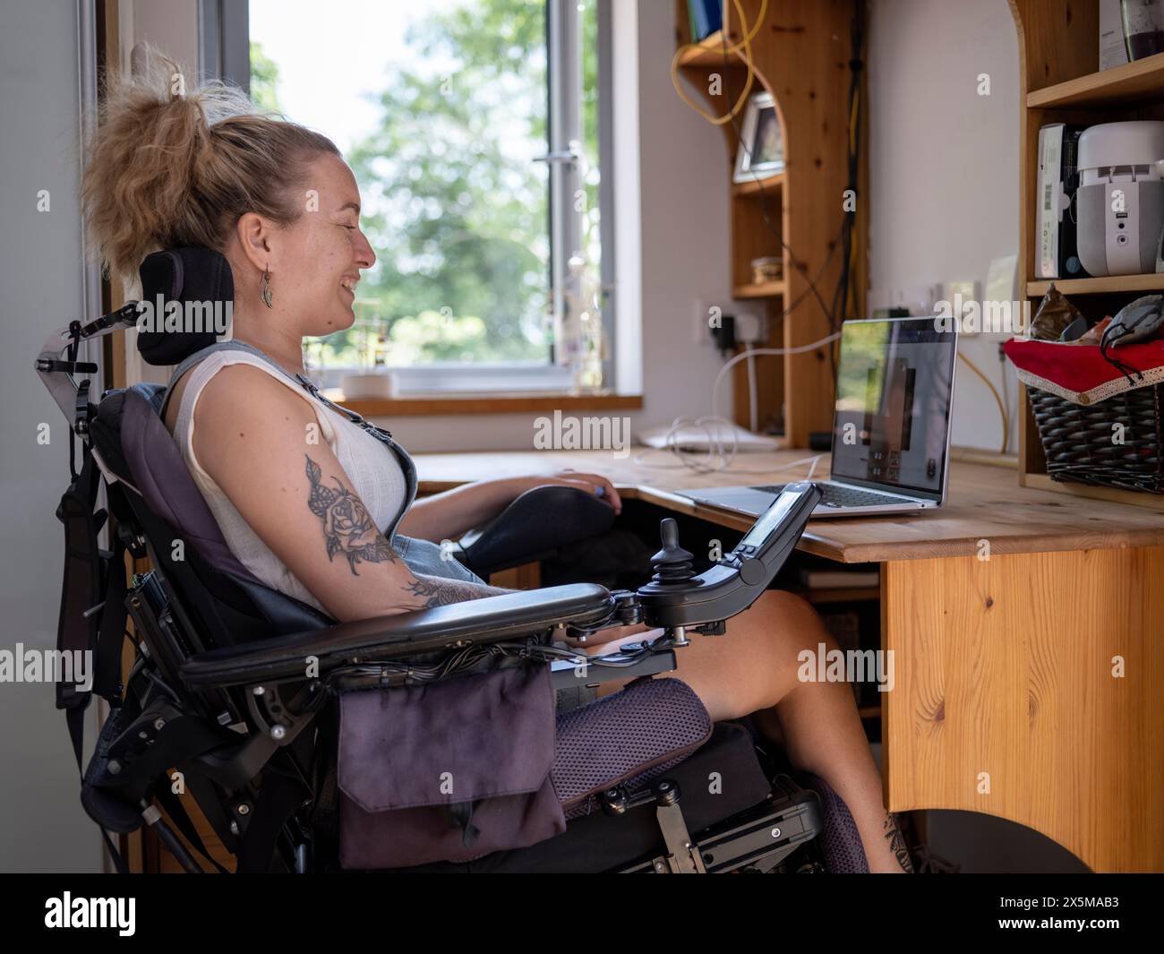 Frau im elektrischen Rollstuhl, die an einem Laptop arbeitet Stockfoto