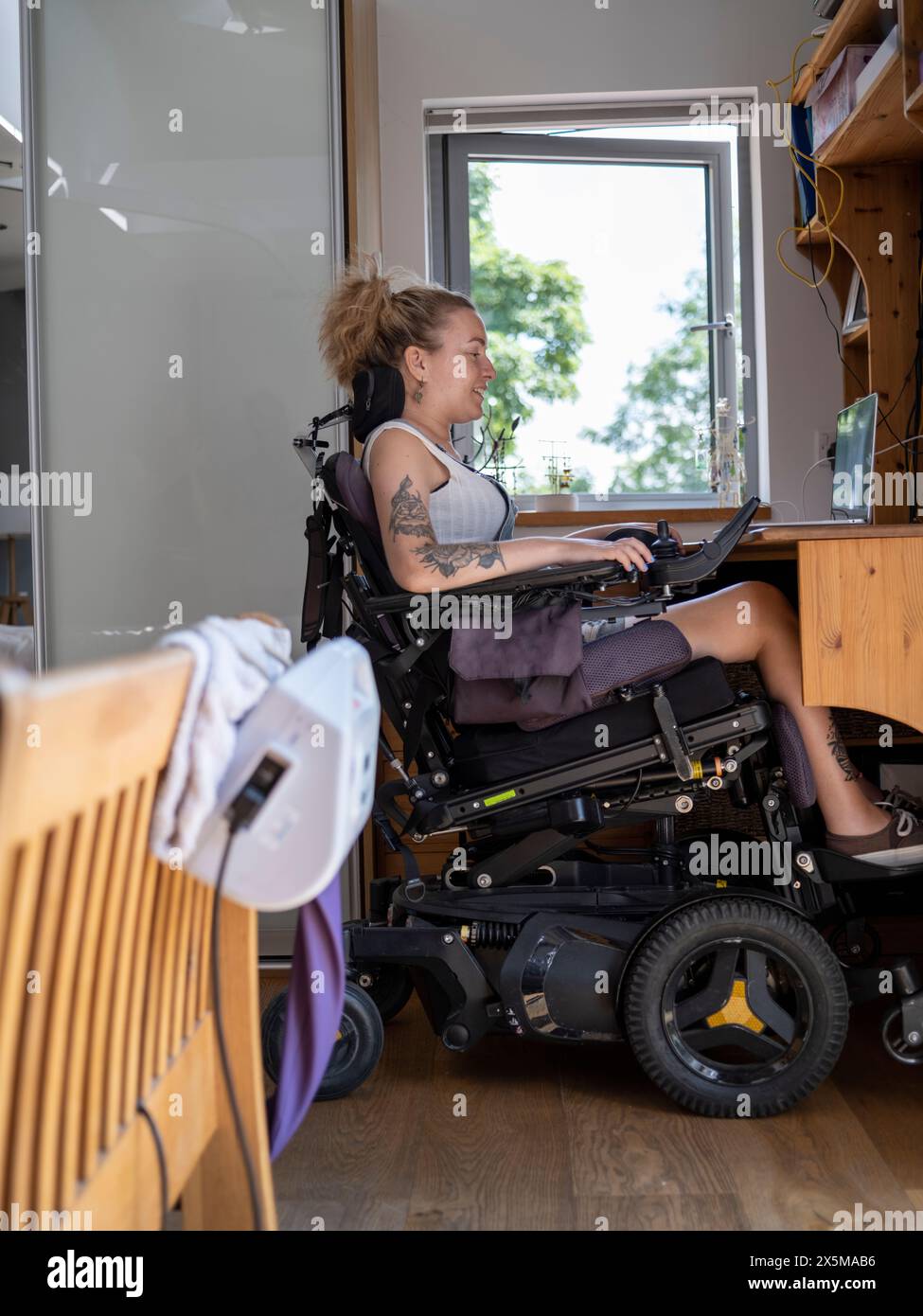 Frau im elektrischen Rollstuhl, die an einem Laptop arbeitet Stockfoto