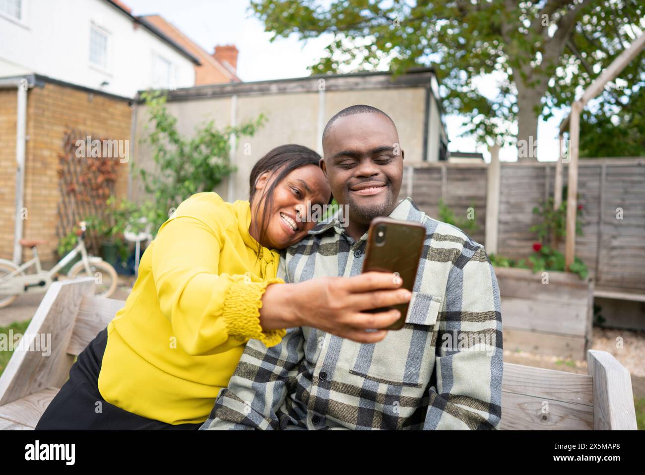 Mutter und erwachsener Sohn mit Down-Syndrom beim Selfie Stockfoto