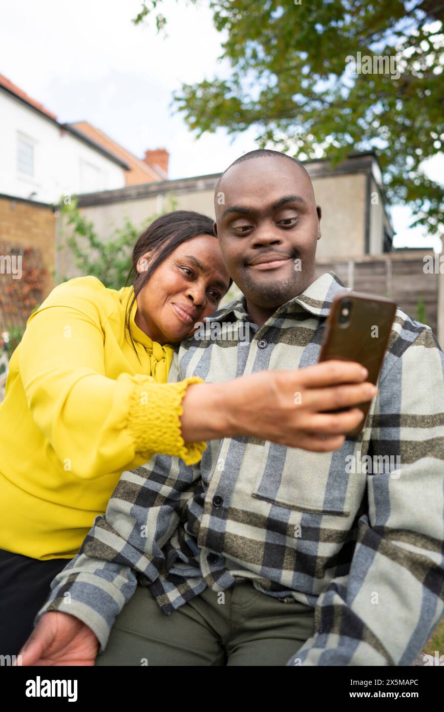 Mutter und erwachsener Sohn mit Down-Syndrom beim Selfie Stockfoto
