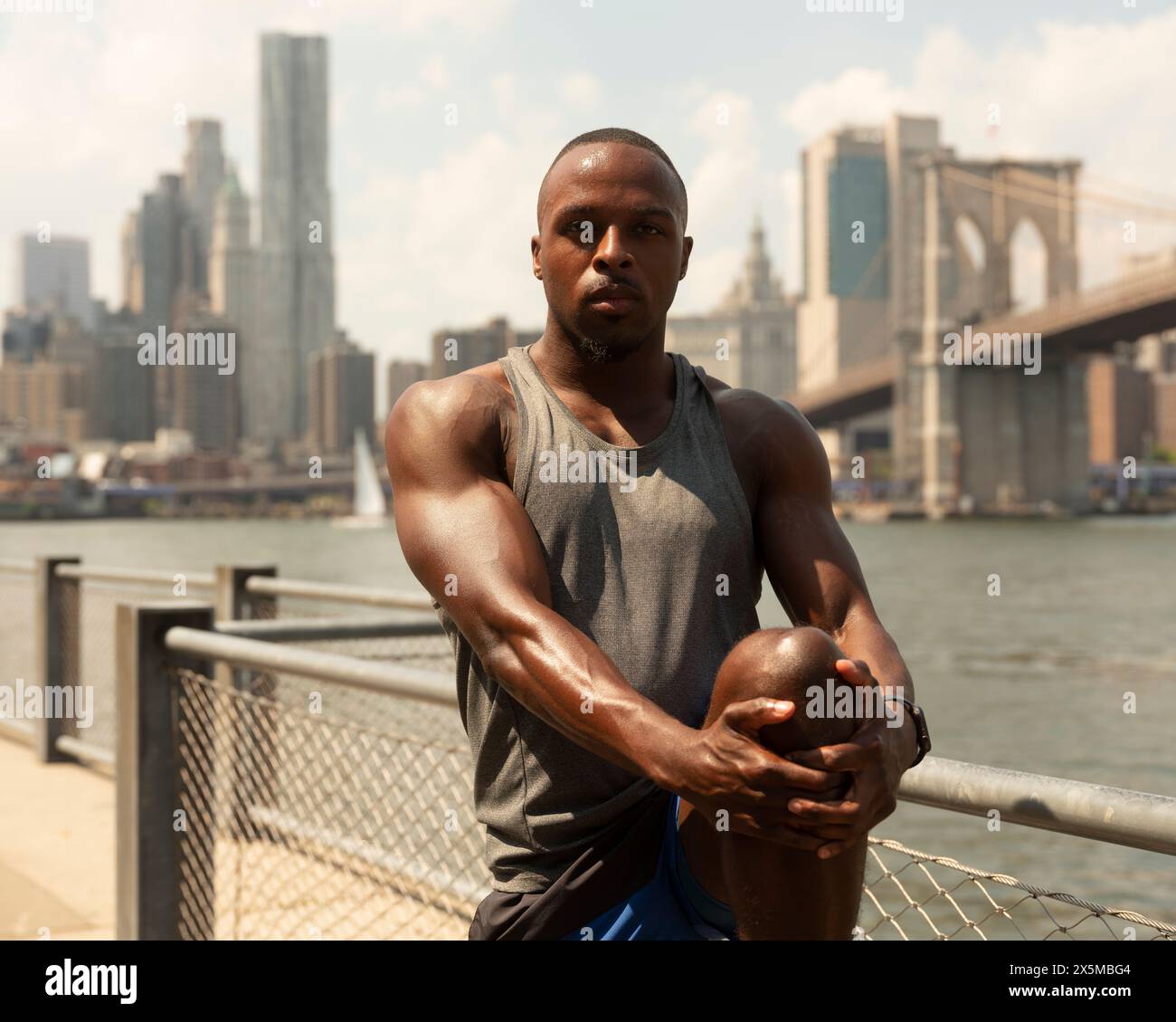 USA, New York City, Athletic man streckt Bein am Fluss Stockfoto