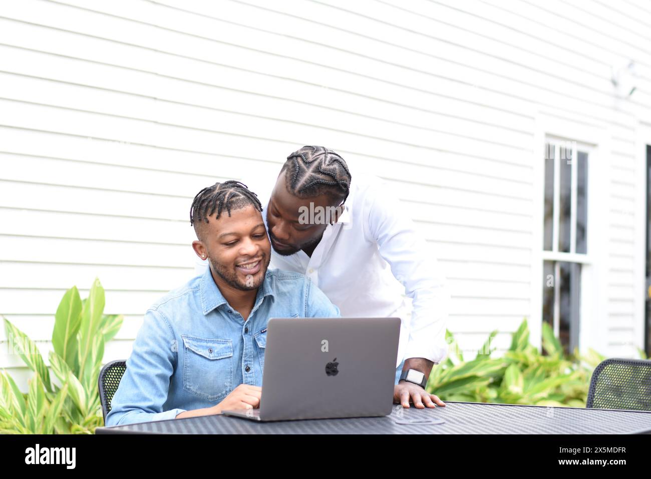 USA, Louisiana, Schwulenpaar, das den Laptop am Hinterhoftisch ansieht Stockfoto